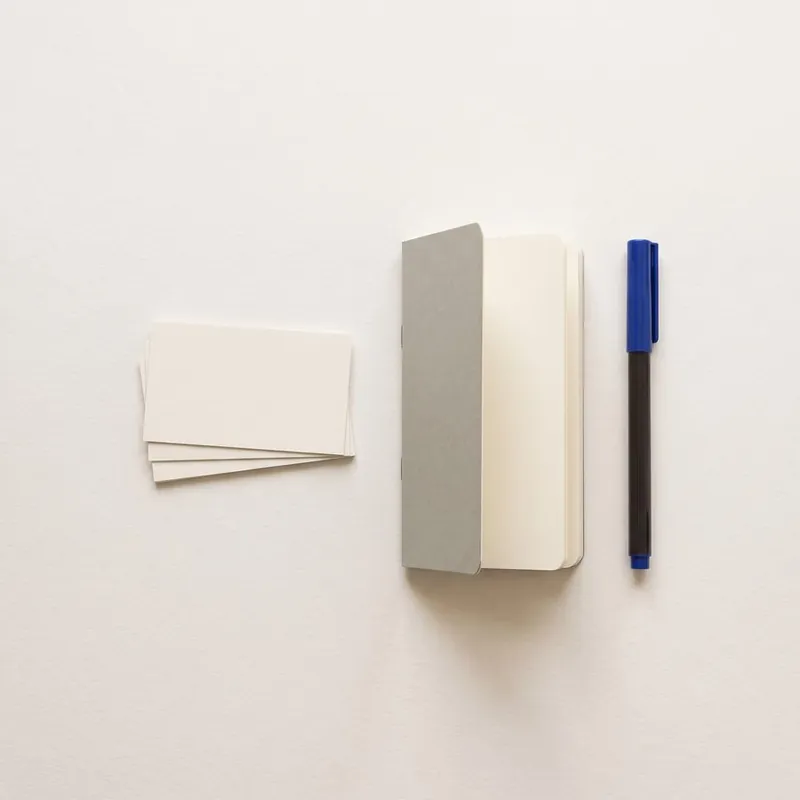 Blank business cards, a notebook and a pen on a desk