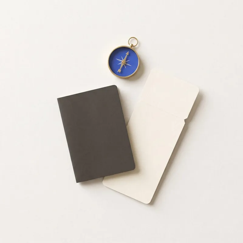 A passport, a boarding pass and a compass laid out on a desk