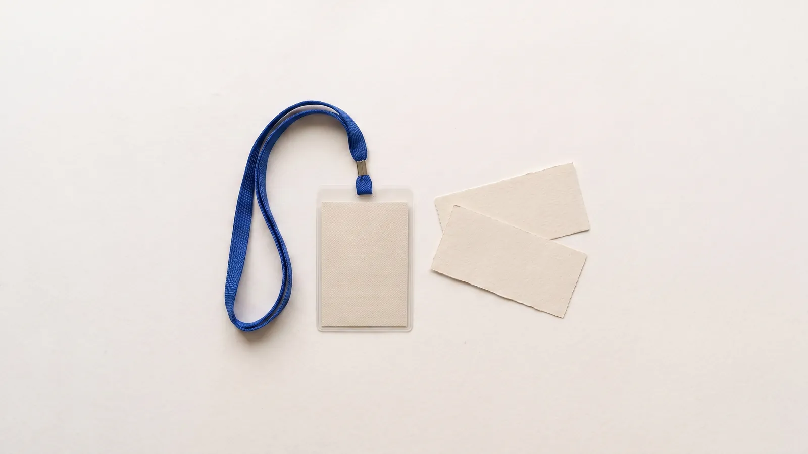 A blank conference badge on a lanyard next to paper tickets