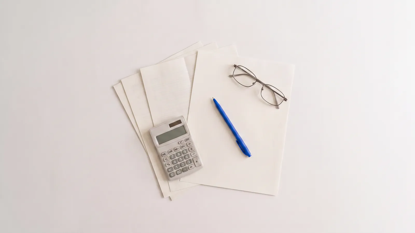 Printed tax forms with a calculator and reading glasses