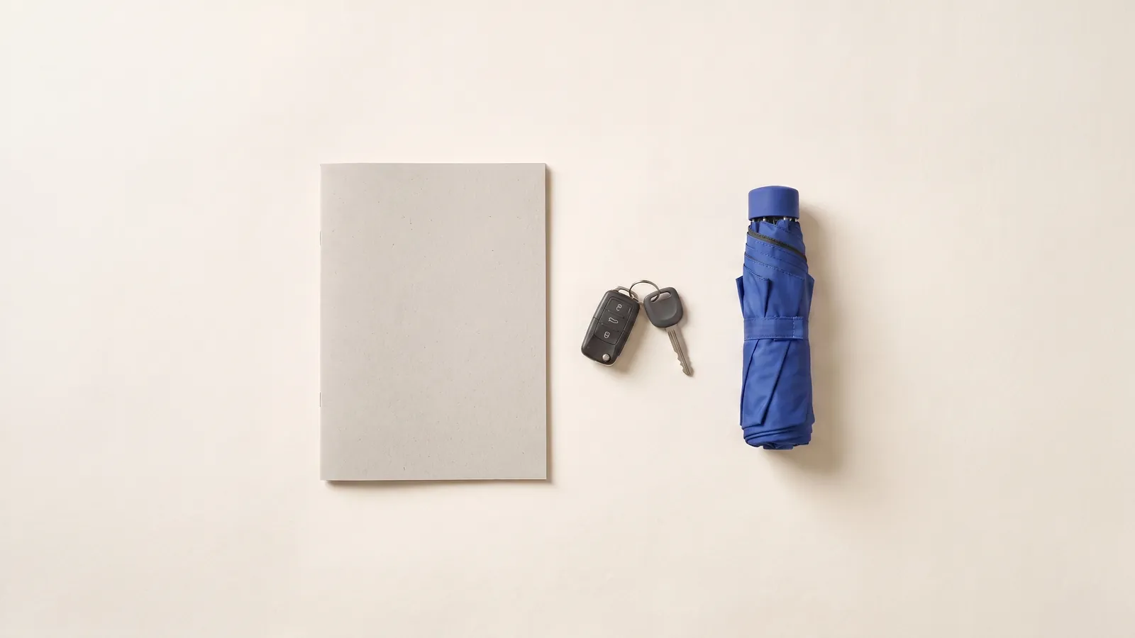 An insurance policy folder with a car key and a folded umbrella