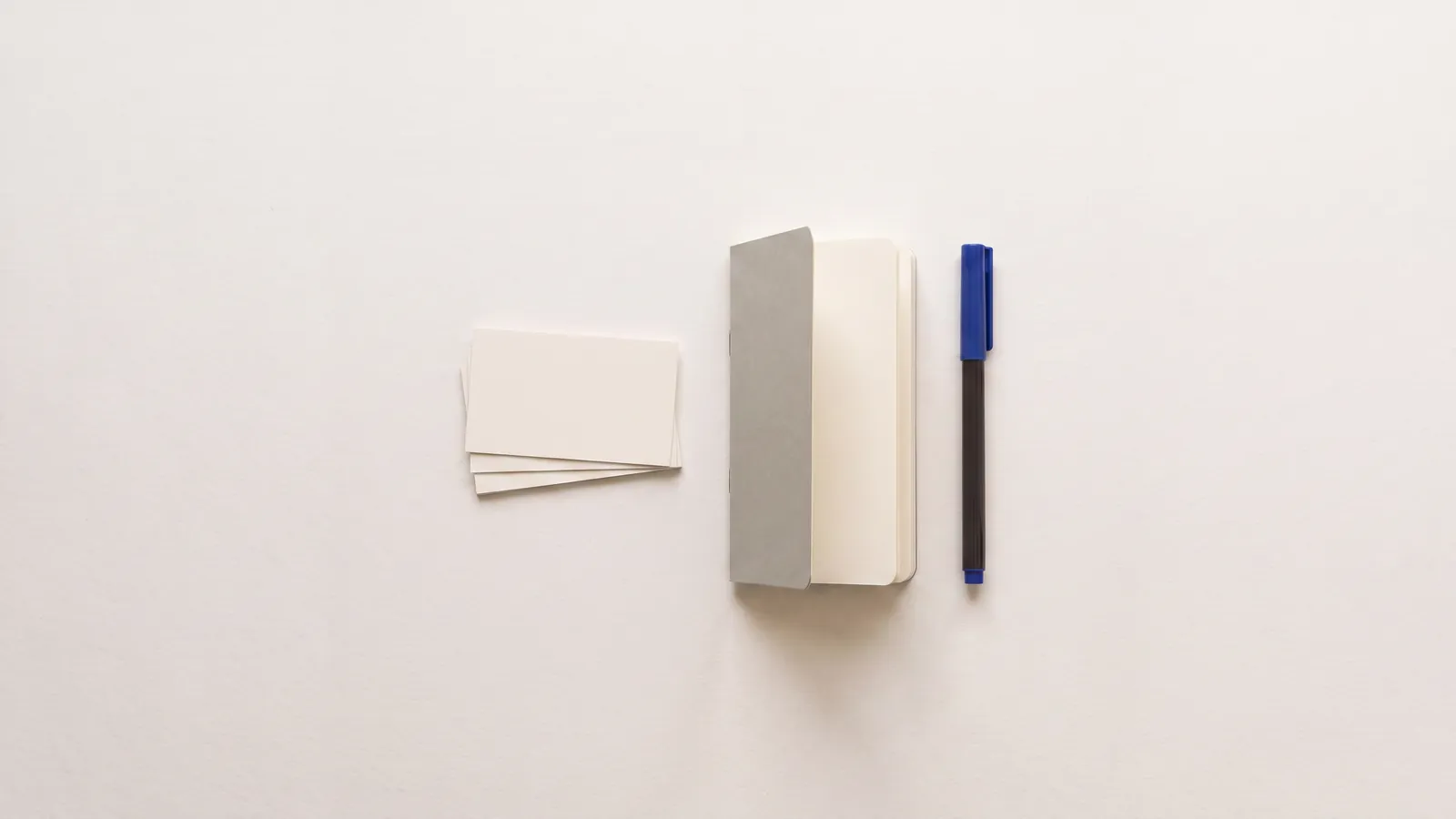 Blank business cards, a notebook and a pen on a desk