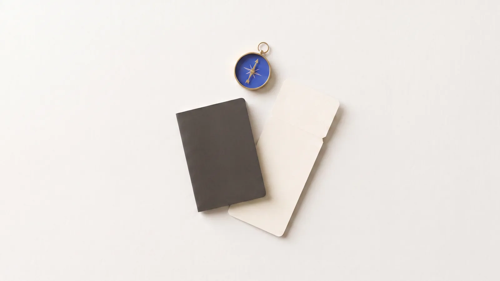 A passport, a boarding pass and a compass laid out on a desk